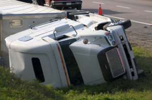 White semi-truck flipped on its side near the road